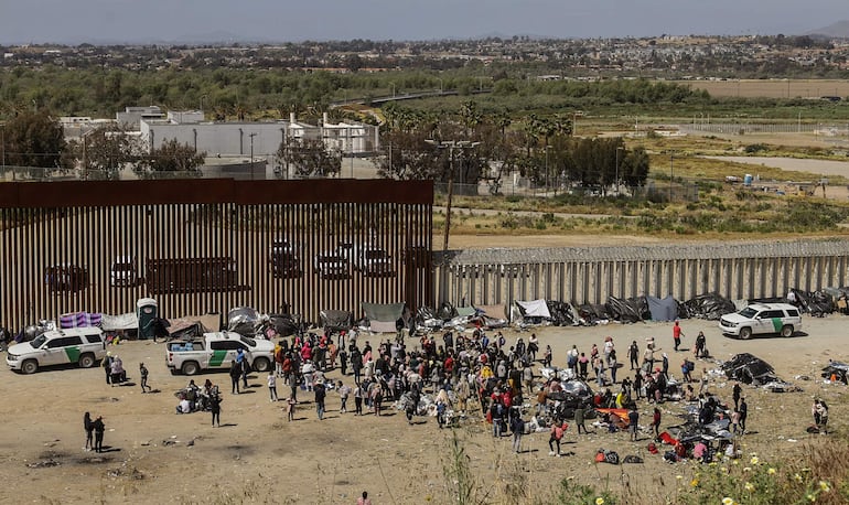 Fotografía general donde se observa a migrantes en un campamento junto al muro fronterizo, el 9 de mayo de 2023, en Tijuana, Baja California (México).