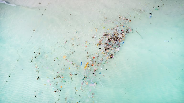 Vista aérea de las aguas oceánicas contaminadas con desechos plásticos. Imagen ilustrativa.