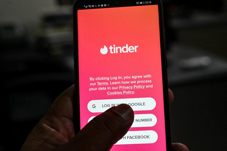 (FILES) This file illustration photo taken on October 6, 2020 shows a user checks the dating app Tinder on a mobile phone in Islamabad. - The company that owns Tinder will pay $441 million to the popular dating app's founders to settle a dispute over the valuation of stock options, documents showed Wednesday. (Photo by Aamir QURESHI / AFP)