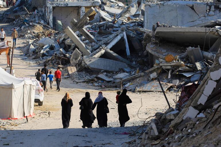 Varias personas caminan entre edificios destruidos en Jan Yunis, Gaza, este jueves.