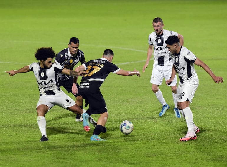 Los jugadores de Tacuary, Amarilla, Riveros y Clar, rodean al gumarelo Matías Schabus.