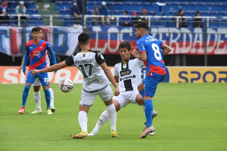 Federico Carrizo, de Cerro Porteño, pelea el balón con dos jugadores de Tacuary.