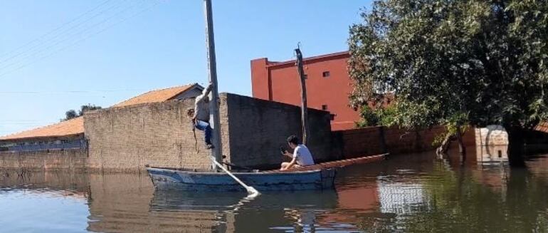 Un solitario funcionario de la ANDE, sube a una columna del tendido eléctrico para realizar cortes en el suministro de la energía, para evitar posible accidente de electrocución en la viviendas sumergidas bajo el agua.