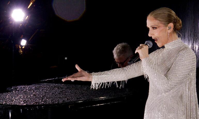 El vestido de Céline Dion demandó unos 500 metros de georgette blanco de seda natural y unas mil horas de confección, dando forma a un diseño que se destacó por sus destellos de cristales, perlas y cuentas de plata en la Torre Eiffel.