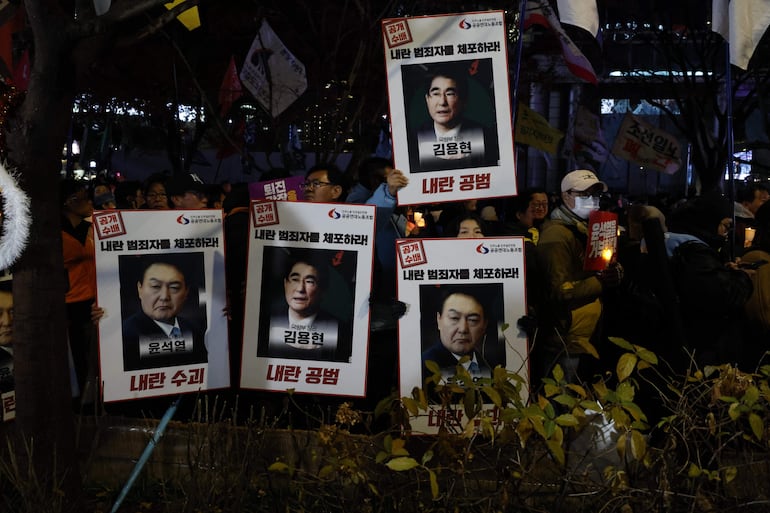 Miembros de grupos cívicos y de la Confederación Coreana de Sindicatos (KCTU) sostienen velas y pancartas pidiendo el arresto del presidente Yoon Suk Yeol y del ex ministro de Defensa Kim Yong-hyun , durante una manifestación en Seúl, Corea del Sur.