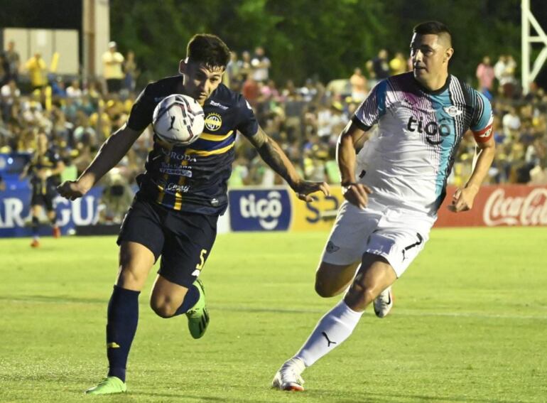 Juan Vera (Trinidense) traslada el balón con el pecho ante la presión de Óscar Cardozo (Libertad).