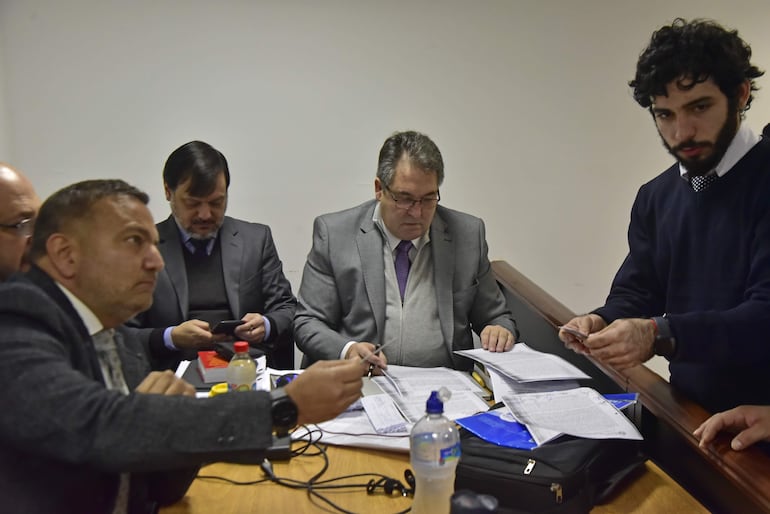 Édgar Alberto Melgarejo Ginard (de saco gris), extitular de la Dinac, y los abogados Claudio Lovera y Andrés Casatti durante la audiencia de hoy.