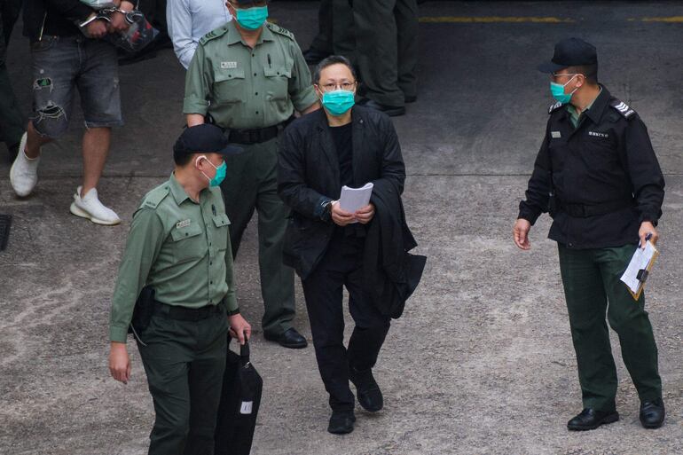 El activista prodemocracia, Benny Tai (C) camina custodiado por las fuerzas dirigidas ahora por el régimen de Pekín.