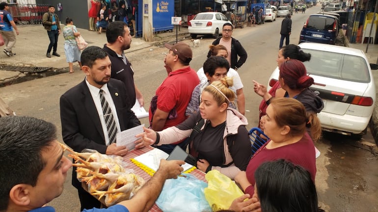 Funcionarios de la Municipalidad tratan de convencer a vendedores de pollos para despejar la vereda de la calle Capitán Bado.