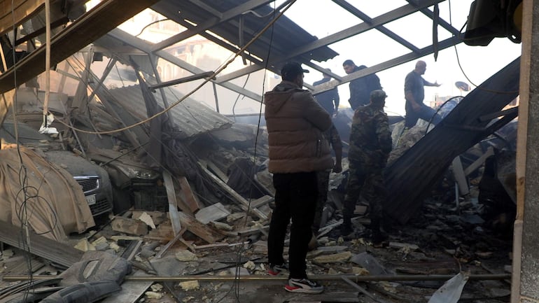 Las fuerzas de seguridad sirias inspeccionan los daños en el lugar de un ataque aéreo en el barrio de Al-Mazzeh de Damasco, Siria.