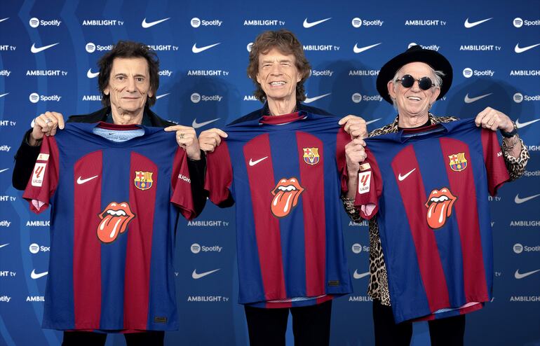 Ronnie Wood, Mick Jagger y Keith Richards, integrantes de los Rolling Stones, exhiben sonrientes las camisetas del Barcelona con el logotipo de la lengua y los labios de la famosa banda británica.