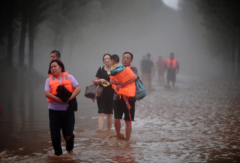 Un grupo de personas evacúa una zona inundada de la ciudad de Baoding, en la provincia china de Hebei, el pasado martes.