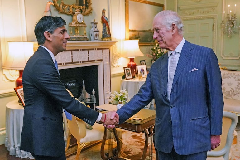 El rey Carlos III (R) de Gran Bretaña le da la mano mientras da la bienvenida al primer ministro británico, Rishi Sunak, en el Palacio de Buckingham, en el centro de Londres, el 21 de febrero de 2024, para su primera audiencia en persona desde el diagnóstico de cáncer del rey.