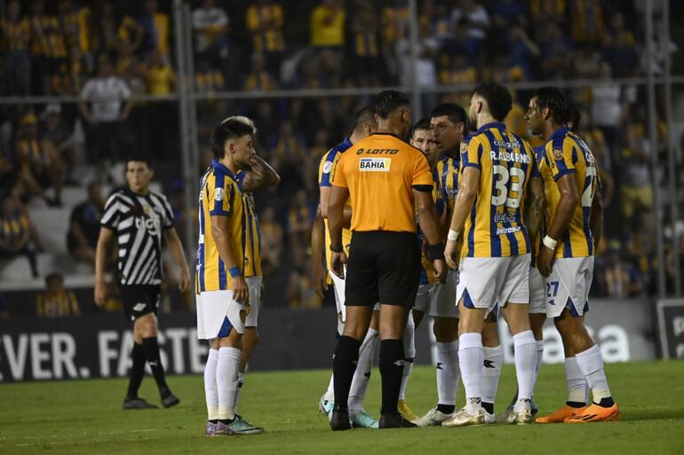 Los jugadores del Sportivo Luqueño reclaman al árbitro Blas Romero en un partido frente a Libertad por la segunda fecha del torneo Apertura 2024 del fútbol paraguayo en el estadio La Huerta, en Asunción.