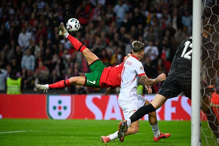 Portugal's forward Cristiano Ronaldo (L) scores their fifth goal during the UEFA Nations League, League A, Group 1 football match between Portugal and Poland at the Dragao stadium in Porto, on November 15, 2024. (Photo by Miguel RIOPA / AFP)