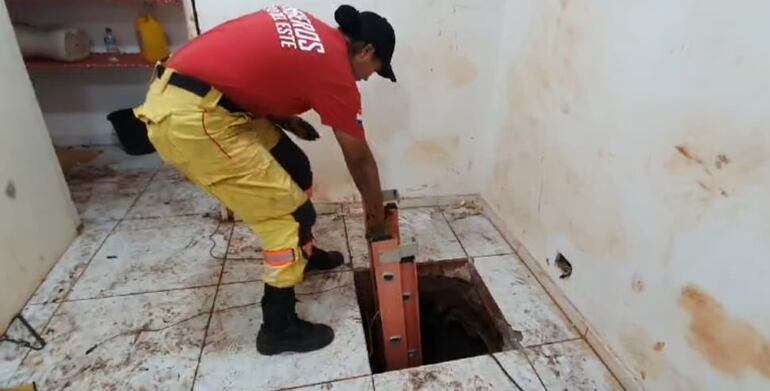 La boca del túnel que condujo a los delincuentes hasta la bóveda de la Asociación de Trabajadores Cambistas se encuentra en el interior del local allanado. En la imagen, el momento en que una bombera extrae una escalera del conducto.