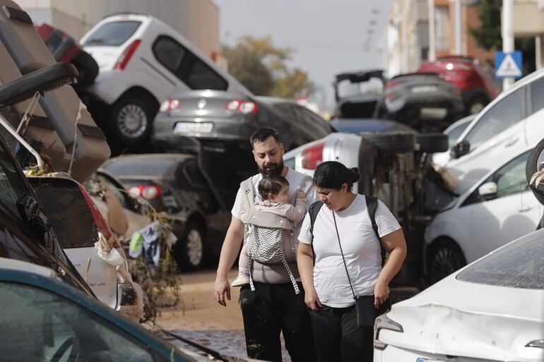 Una pareja con su bebé camina entre una montaña de coches hacinados tras las inundaciones sufridas en la localidad valenciana de Paiporta. La Comunitat Valenciana intenta recuperarse de la peor dana del siglo en España, que ha dejado casi un centenar de muertos en esa región, además de un inmenso escenario de daños en carreteras, calles e infraestructuras de numerosas localidades.