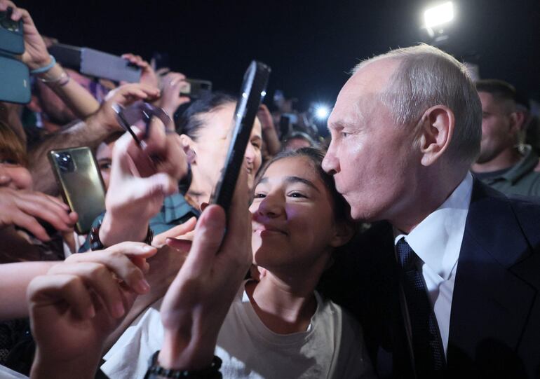 El presidente de Rusia, Vladimir Putin, besa a una joven seguidora durante un acto en Moscú. (Sputnik/AFP)