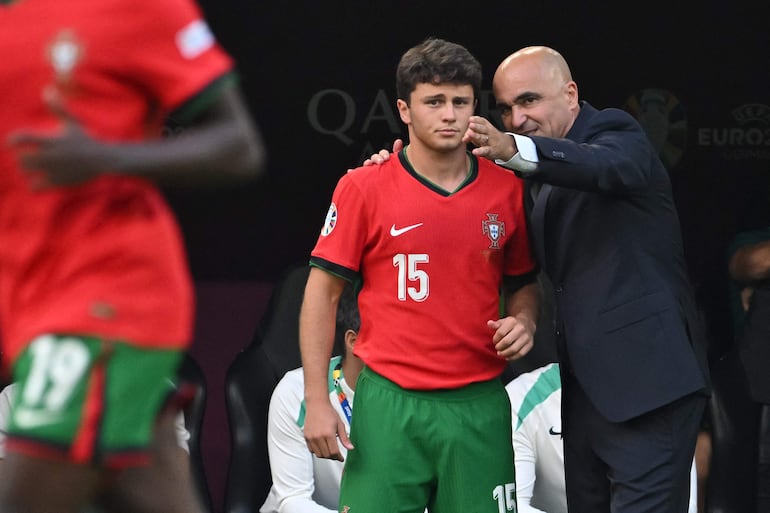 Portugal's head coach Roberto Martinez speaks with Portugal's midfielder #15 Joao Neves during the UEFA Euro 2024 Group F football match between Turkey and Portugal at the BVB Stadion in Dortmund on June 22, 2024. (Photo by Miguel MEDINA / AFP)