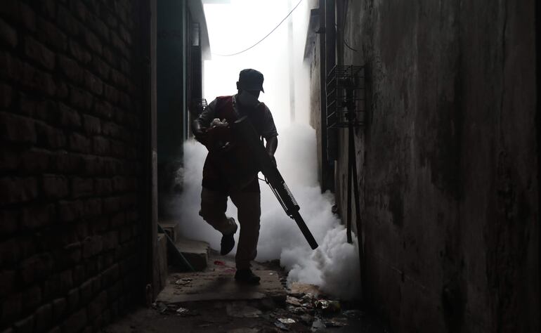 Trabajador de la municipalidad esparciendo veneno para matar al vector que transmite dengue.