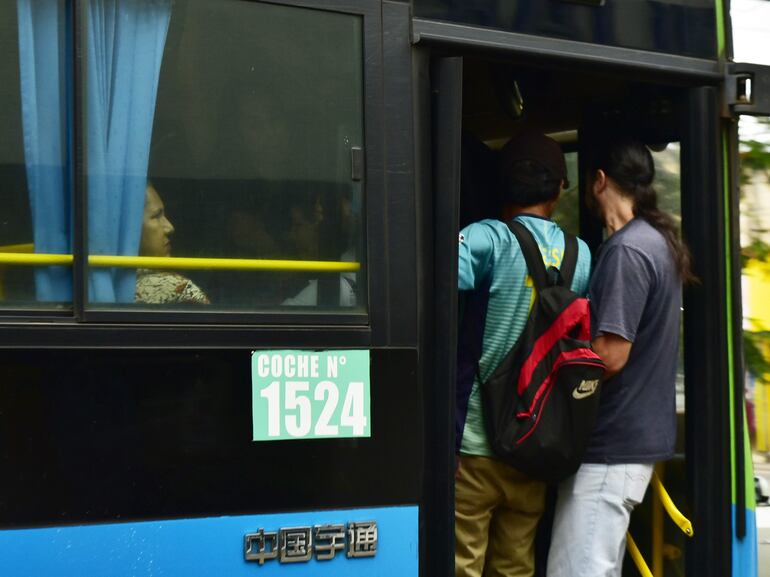 Pasajeros viajan en la estribera del colectivo, arriesgando su vida con tal de llegar ya a destino. 