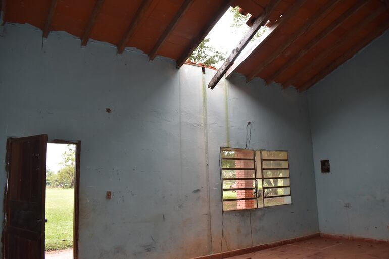 Un grupo de niños se guarecen de las bajas temperaturas en este salón con parte del techo caído y en peligro de desplome.