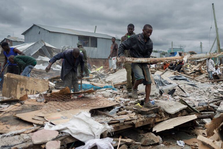 Los residentes hurgan en láminas de metal y postes de madera de chozas que han sido demolidas por las agencias de seguridad estatales en el barrio marginal de Mukuru en Nairobi el 8 de mayo de 2024. Las agencias de seguridad de Kenia continuaron demoliendo casas cerca de las orillas de los ríos en Nairobi mientras las inundaciones causan estragos en el país.