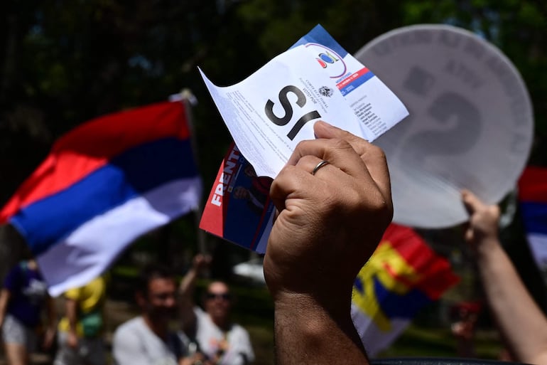 Un partidario del candidato presidencial de Uruguay por el partido izquierdista Frente Amplio, Yamandu Orsi, sostiene un volante de propaganda instando a la gente a votar "sí" en un plebiscito sobre la reforma de las pensiones durante un mitin de campaña en Montevideo el 20 de octubre de 2024. Uruguay celebrará elecciones presidenciales el 27 de octubre.