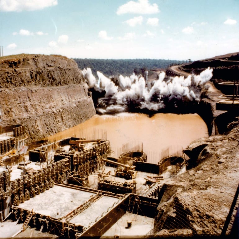 Los diques o ataguías de aguas arriba de aguas abajo que protegían el canal de desvío del río Paraná, volaban en pedazos,  el caudaloso río abandonaba su antiguo sitial para que se inicien las obras principales del futuro complejo.