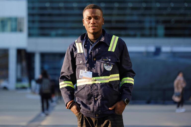 Johnson Doe, 39, de Ghana, posa frente al centro de convenciones Bexco en Busan, donde se están llevando a cabo negociaciones internacionales sobre un tratado vinculante contra la contaminación por plásticos.