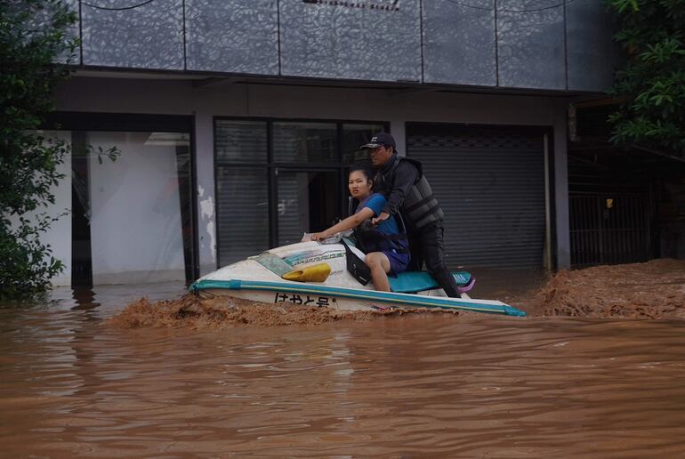 Rescatista traslada en jet ski a una mujer por una zona inundada el jueves, en el norte de Tailandia.