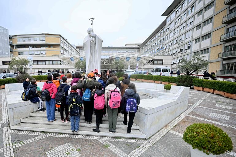 Un grupo de niños y jóvenes elevan una oración por la salud del Papa Francisco, en una plaza en Roma. 