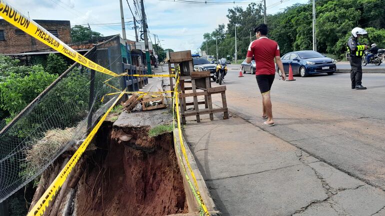 Transeúntes caminan sobre la calzada por el desmoronamiento en la cabecera del puente Ka'i.