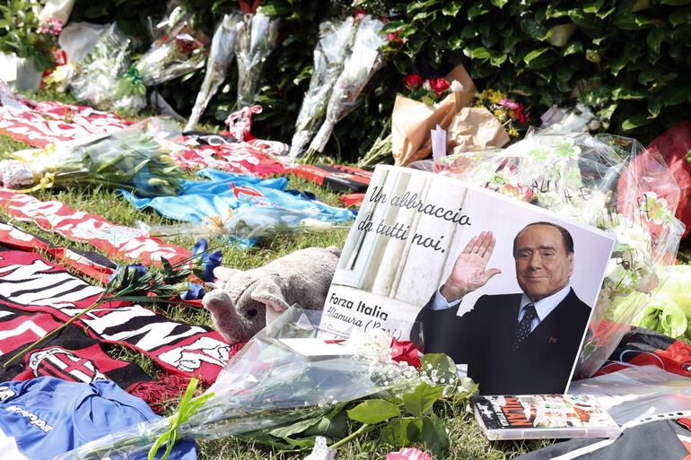 Flores, fotos y recuerdos de Silvio Berlusconi son dejados por sus admiradores en las afuera de la Villa San Martino de Arcore.