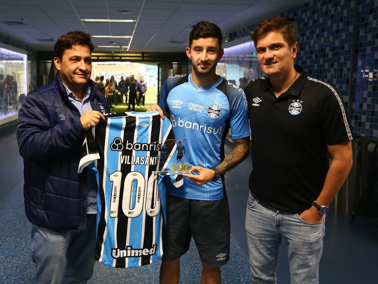 El paraguayo Mathías Villasanti (c), futbolista de Gremio de Porto Alegre, recibe la camiseta con el número 100 en el Arena do Gremio, en Porto Alegre, Brasil.