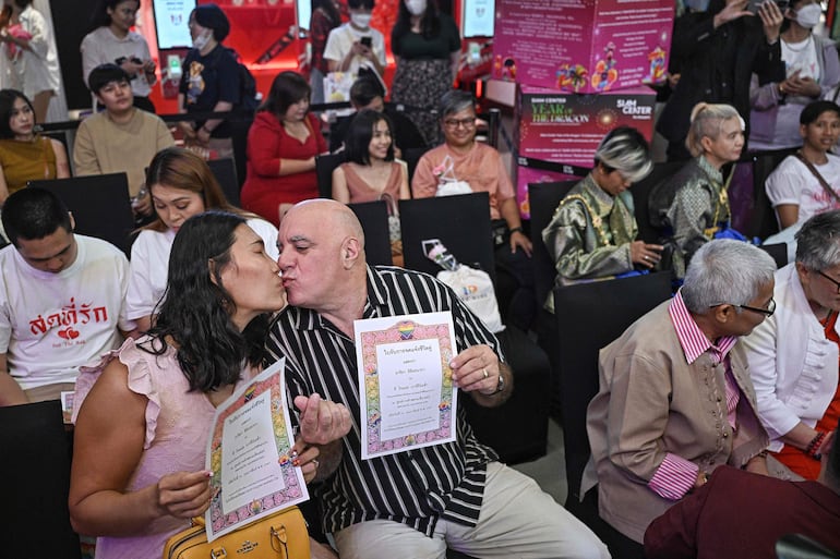 Ariya Milintanapa (izq.) y su compañero Lee Ronald Battiata (segundo izq.) se besan mientras se sientan con otras parejas durante una ceremonia para casar extraoficialmente a parejas LGBTQ el día de San Valentín en Bangkok el 14 de febrero de 2024.