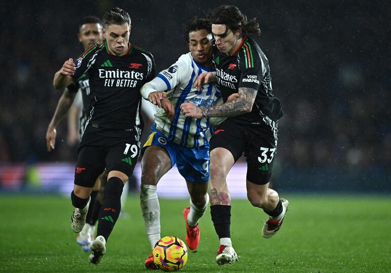 Brighton (United Kingdom), 04/01/2025.- Brighton's Joao Pedro (C) in action against Arsenal's Leandro Trossard (L) and Riccardo Calafiori (R) during the English Premier League match between Brighton & Hove Albion and Arsenal FC, in Brighton, Britain, 04 January 2025. (Reino Unido) EFE/EPA/VINCE MIGNOTT EDITORIAL USE ONLY. No use with unauthorized audio, video, data, fixture lists, club/league logos, 'live' services or NFTs. Online in-match use limited to 120 images, no video emulation. No use in betting, games or single club/league/player publications.
