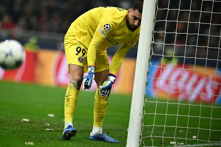 Paris Saint-Germain's Italian goalkeeper #99 Gianluigi Donnarumma removes rolls of fake dollars from his door during the UEFA Champions League 1st round group F football match between AC Milan and Paris Saint-Germain at the San Siro stadium in Milan on November 7, 2023. (Photo by GABRIEL BOUYS / AFP)