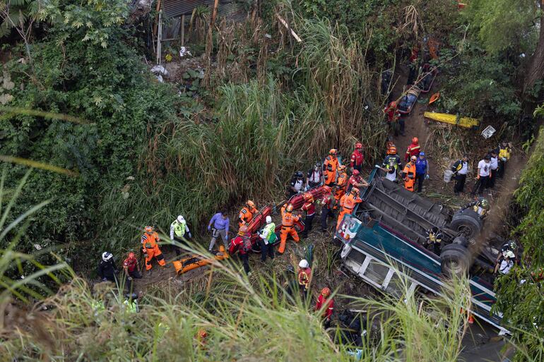 Integrantes de organismos de socorro trabajan en la zona donde ocurrió el accidente de un autobús, que cayó en un río de aguas residuales este lunes en el norte de la Ciudad de Guatemala (Guatemala). 