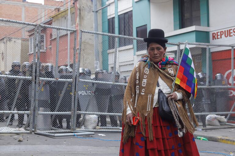 Una mujer campesina afín al expresidente Evo Morales camina frente a policías durante unos enfrentamientos, en el centro de La Paz (Bolivia).