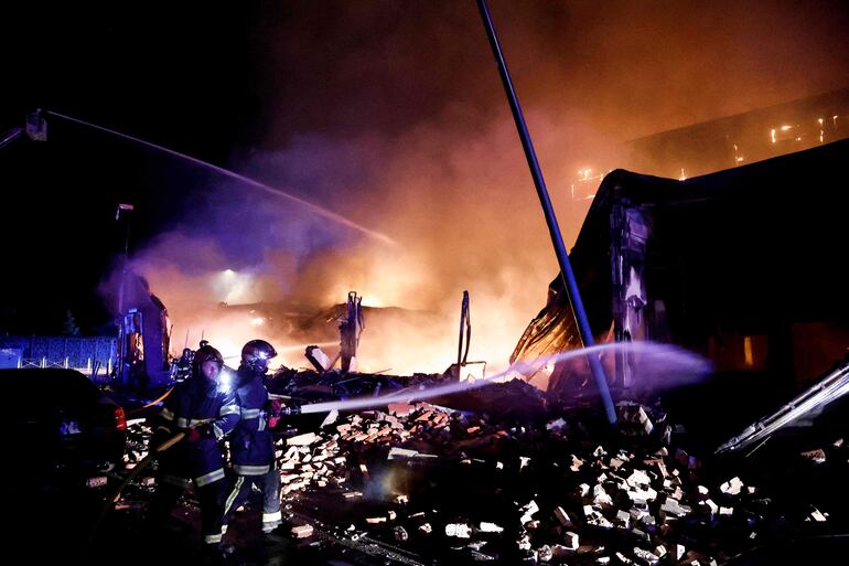 Bomberos combaten el fuego presuntamente ocasionado por manifestantes en un suburbio de París.  (AFP)