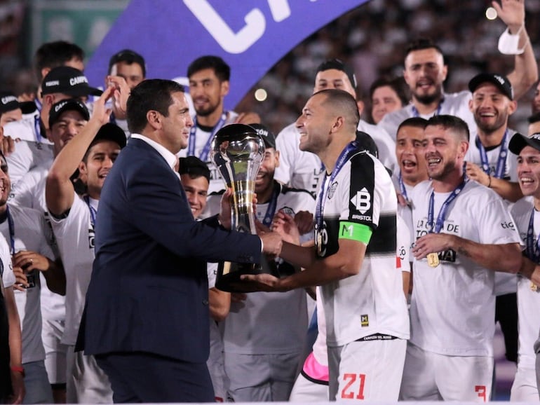 Robert Harrison (i) entrega la Copa Paraguay a Antolín Alcaráz, capitán de Olimpia.