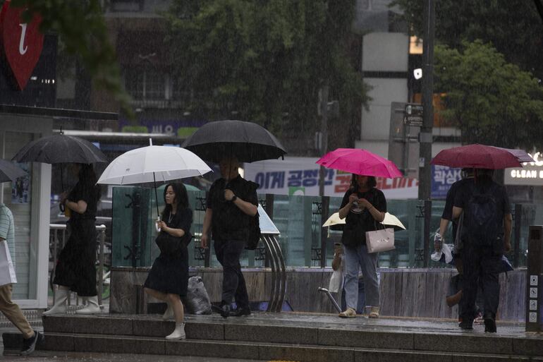 Personas caminan con paraguas en medio de una intensa lluvia en la plaza Gwanghwamun de Seúl, Corea del Sur.