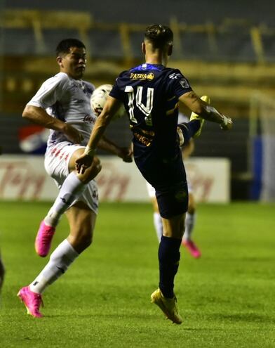 Feliciano Brizuela (Nacional) disputa el balón con Joel Román (Trinidense).