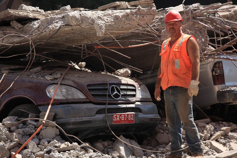 Chile: trabajador cerca de un SUV Mercedes Benz en un estacionamiento aplastado por el piso de un edificio durante el terremoto de 8,8 del 27 de febrero de 2010.