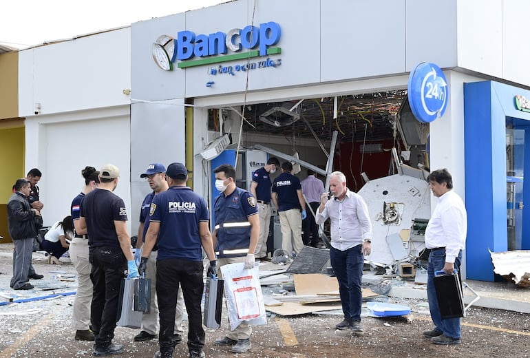 Policías y empleados del banco Bancop de Naranjal aparecen frente a la sucursal que fue detonada por los asaltantes que robaron más de G. 2.800 millones.