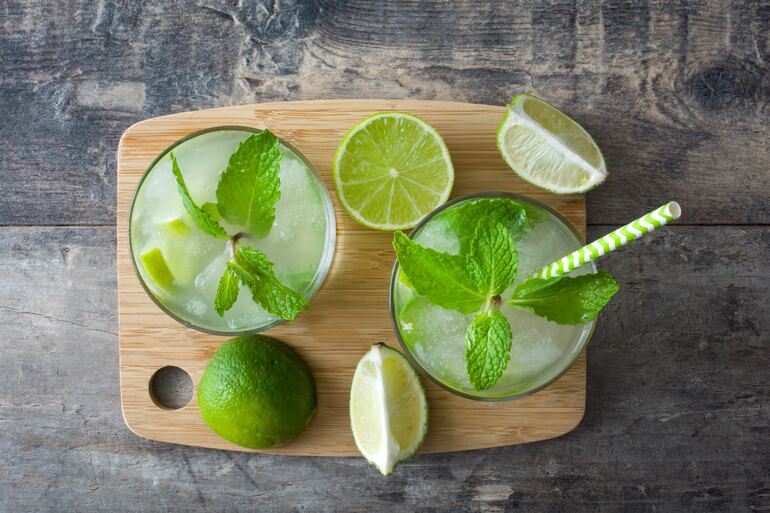 Dos vasos de Mojito frozen vistos desde arriba, rodeados de rodajas de limón y decorados con menta, sobre una tabla de madera