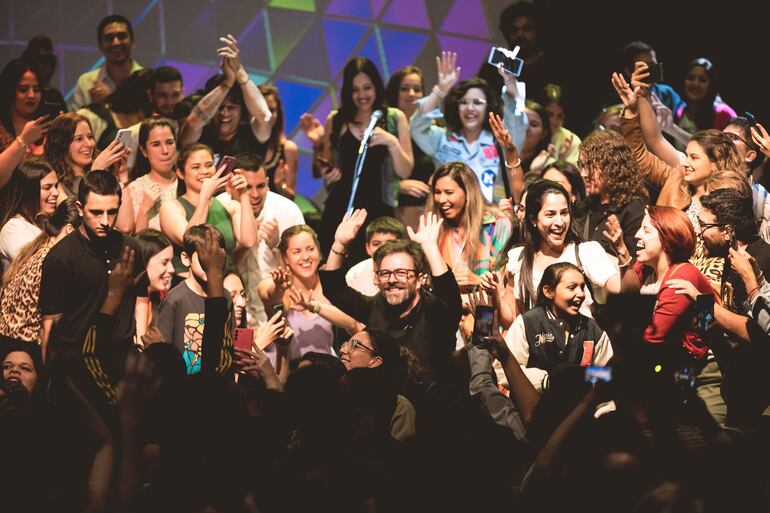 Kevin Johansen saludando, levantando las manos, mientras es rodeado por el público hacia casi el final de la fiesta.