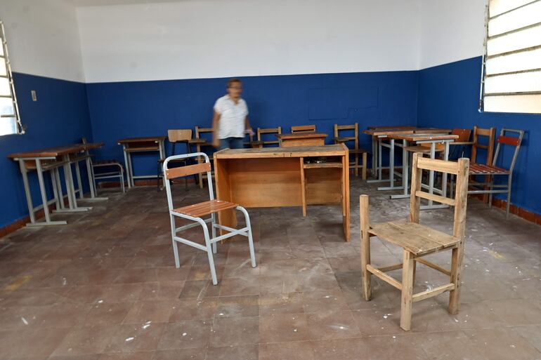 La directora del Colegio Trinidad, Gloria Morai, recorre una sala de clase con algunos pupitres en mal estado.