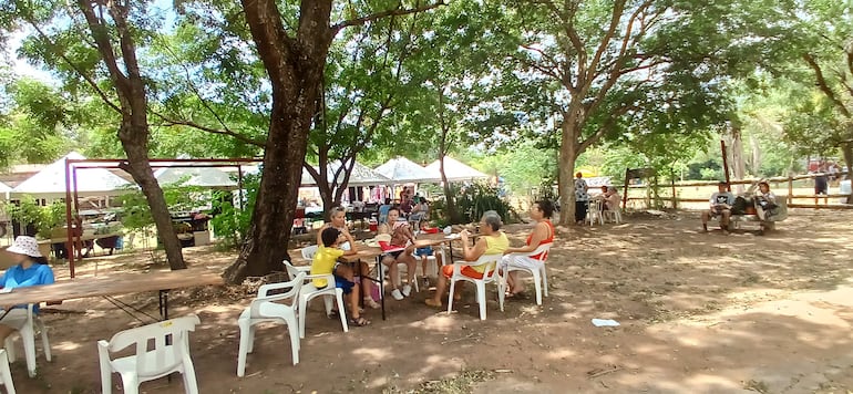 personas comiendo bajo árboles